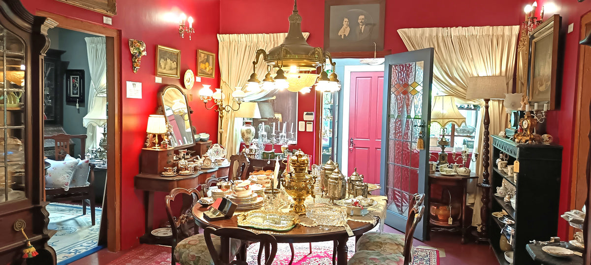 The red room at The Dancing Faun Antiques, with a round dining table set with silver, porcelain and crystal